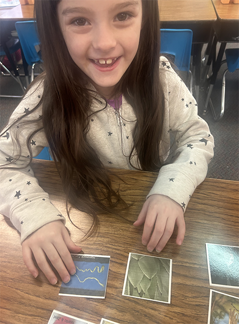 Smiling first grader sorting photos