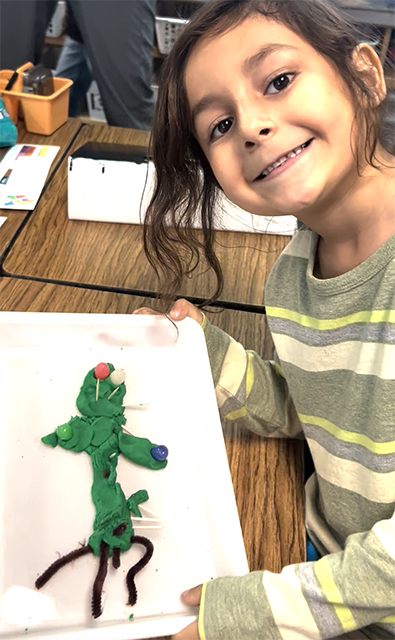 Smiling first grader holding saguaro craft